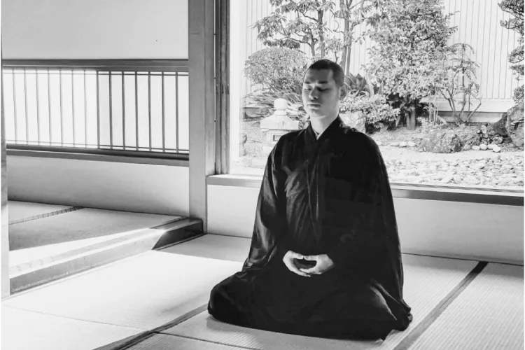 障子の差し込む光のなか、和室で坐禅をする僧侶